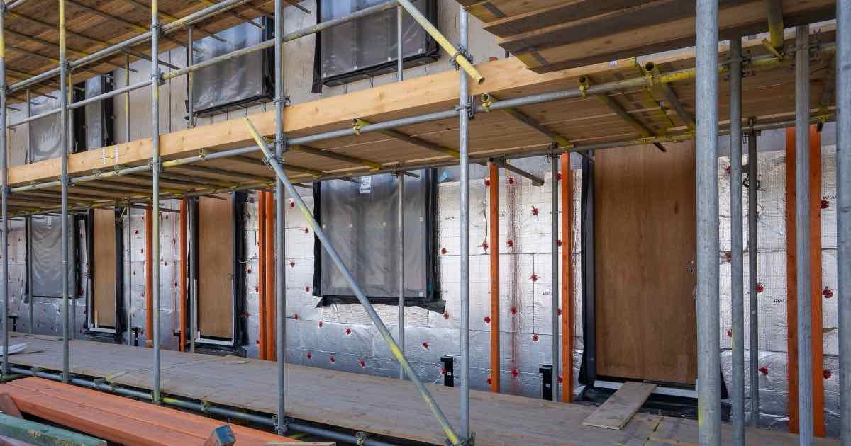 Gevel in aanbouw met isolatieplaten achter een stelling