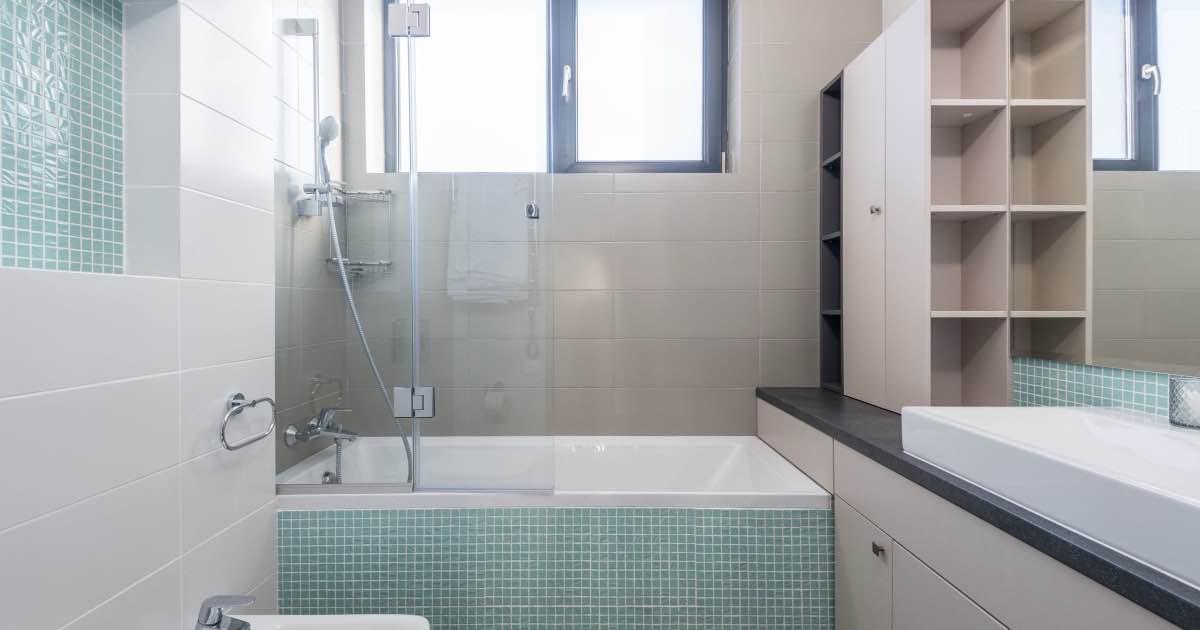 Badkamer met ligbad, glazen wand en lichte tegels