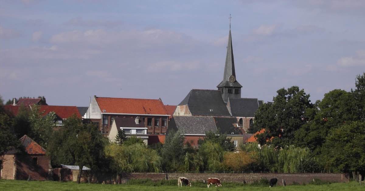Kerk en huizen van Vlezenbeek (Sint-Pieters-Leeuw) achter een weiland